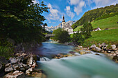 Pfarrkirche St. Sebastian mit der Ramsauer Ache, die nördlich des Nationalparks Berchtesgaden durch das Tal fließt; Berchtesgadener Land, Ramsau, Bayern, Deutschland