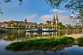 Outlook over the Danube River with the Gothic St Peter's Cathedral from the Marc?-Aurel-shore in the Old Town of Regensburg with a blue sky at sunset; Regensburg, Bavaria, Germany
