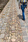 Eine Person geht einen Steinweg entlang; Cusco Peru