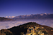 Nepal, Nagarkot, Overview Of Niva Lodge On Hillside, Cloud Line And Himalayan Range In Background.