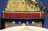 Nepal, Close-up of painted eyes on Boudhanath Stupa and colorful streaming flags; Kathmandu