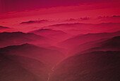 Nepal, Kathmandu-Tal, Fluss fließt zwischen Bergen bei Sonnenuntergang, rotes Nebellicht.