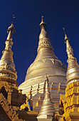 Birma (Myanmar), Yangon, Shwedagon Paya, Nahaufnahme von drei goldenen Steeples im Sonnenlicht.