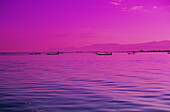 Burma (Myanmar), Inle-See, rosa und violetter Sonnenuntergang, Reflexionen auf gekräuseltem Wasser, Fischer in der Ferne.