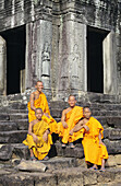 Cambodia, Siem Reap, Agnkor Thom, Bayon Temple With Four Monks Sitting On Stairs