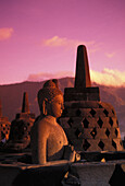 Indonesien, Java, Borobudor-Tempel und Buddha-Statue bei Sonnenaufgang, rosafarbener, nebliger Himmel