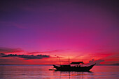 Philippinen, Insel Boracay, Outrigger-Kanu bei Sonnenuntergang, lila-orangefarbener Himmel