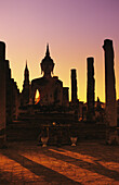 Thailand, Sukhothai, Wat Mahathat, Buddha und Säulen im Gegenlicht bei Sonnenuntergang