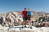 Männliche und weibliche Wanderer auf dem Gipfel eines Felsens mit abgerundeten Felsformationen im Hintergrund und blauem Himmel; Palm Springs Kalifornien Vereinigte Staaten von Amerika