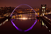 Ein leuchtender violetter Bogen auf einer Brücke über den Fluss Tyne, nachts beleuchtet; Newcastle Northumberland England