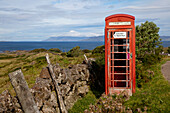 Eine rote Telefonzelle neben der Straße an der Küste; Argyll Schottland