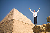 Eine Touristin hebt ihre Arme vor den Pyramiden von Gizeh in der Nähe von Kairo; Gizeh Ägypten