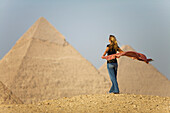 A Female Tourist Holds A Silk Scarf In The Wind As She Looks Out Toward The Pyramids Of Giza Near Cairo; Giza Egypt