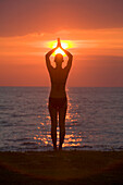 Eine Touristin macht Yoga und Dehnübungen bei Sonnenuntergang am Strand einer tropischen Insel; Koh Lanta Thailand