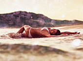 A Woman In A Bikini Lays On The Wet Sand; Tarifa Cadiz Andalusia Spain