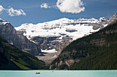 Mount Victoria And Lake Louise With Canoes In The Distance And Blue Sky With Clouds; Lake Louise Alberta Canada