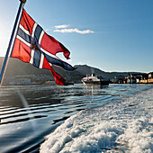 Norwegens Flagge weht auf der Rückseite des Bootes im Hafen; Bergen Norwegen
