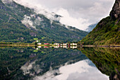 Berge und Wolken spiegeln sich im ruhigen Wasser des Granvinsvatnet mit Häusern am Wasser; Granvin Hordaland Norwegen