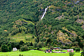 Häuser in einem Tal mit einem Wasserfall am Berghang; Flam Aurland Norwegen