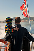 Ein Vater und sein Sohn fahren auf dem Rücken eines Bootes; Fjord Norwegen