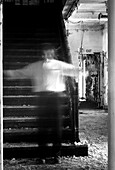 Transparenter Mann mit ausgestreckten Armen steht auf der Treppe eines verlassenen Gebäudes