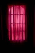 Tageslicht strömt durch rote Vorhänge am Fenster