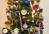 Nahaufnahme eines mit Zuckerstangen und Weihnachtskugeln geschmückten Weihnachtsbaums