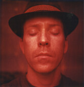 Kopf- und Schulterporträt eines mittelgroßen Mannes mit Hut und geschlossenen Augen