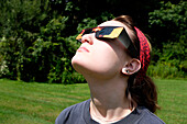 Jugendliches Mädchen mit Sonnenfinsternisbrille bei der Betrachtung einer partiellen Sonnenfinsternis