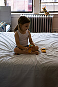 Junger Junge sitzt auf dem Bett und spielt mit Spielzeug