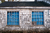 Verfallenes Holzschindelgebäude mit mit blauer Plane abgedeckten Fenstern