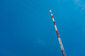 Low Angle View of Communications Tower with Guide Wires against Blue Sky
