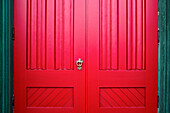 Rote Holztüren mit verzierten Metallgriffen