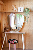 Small dressing table with mirror in room with light-colored wood paneling