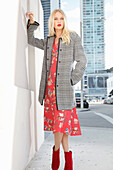Young blond woman in red floral dress and checked coat