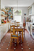 White kitchen with rustic wooden table and chairs, colorful postcard collection on the wall in the background