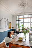 Wooden table with classic chairs in dining room of an old building with stucco ceiling and glass wall