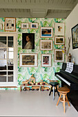 Music room with wall with tropical wallpaper and varied picture gallery