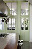 Verglaste Wand mit grün gestrichener Holzumrandung, verglaste Tür mit Holzumrandung, Küche, Blick auf Wohnraum, Industriestil