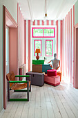 Raum mit rosa-weißen Streifenwänden, bunten Kisten und Holzboden