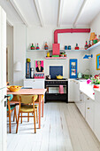 Helle Küche mit farbigen Akzenten und dekorativen Objekten auf Regalen