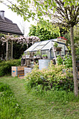 Kleines Gewächshaus mit "Flower Market"-Schild in einem Garten