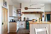 Country kitchen in white with exposed wooden beams and cooking island