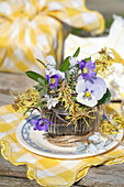 Spring flower bouquet with horned violets (Viola cornuta) and anemones in a glass container