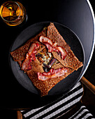 Galette mit Raclettekäse, roten Zwiebeln und knusprigem Speck