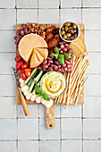 Cheese platter with olives, dip, tomatoes, cucumber, grapes and walnuts