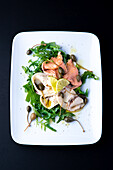 Rocket salad with capers, pickled salmon, and white fish
