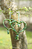 Herzförmiger Kranz aus grünen Blättern an einem Baum im Frühling