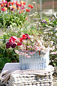 Bag with spring flowers on a blanket and cushions in the garden