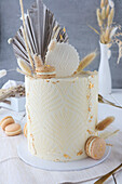 White stencil cake with macarons and gold leaf for a birthday cake